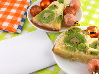 Image showing kiwi cake on plate with white blank paper and christmas balls set