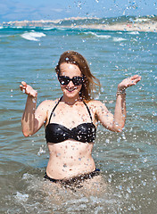 Image showing young beautiful woman in ocean making water splashes