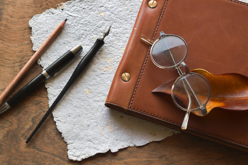 Image showing Busines concept with retro glasses, notebook, ink pen on wooden background