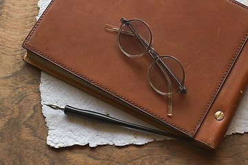 Image showing Busines concept with retro glasses, notebook, ink pen on wooden background