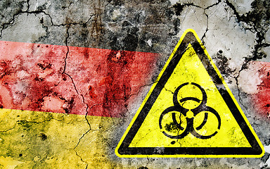 Image showing Old cracked wall with biohazard warning sign and painted flag