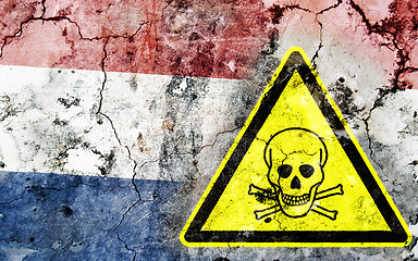 Image showing Old cracked wall with poison warning sign and painted flag