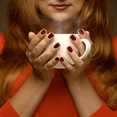 Image showing woman holding hot cup and smiles