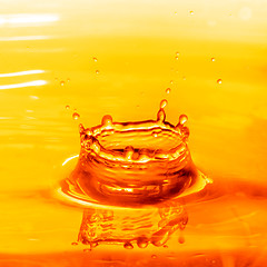 Image showing drop falling into orange water with splash