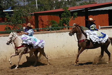 Image showing Two Mexican girls in dresses galloping