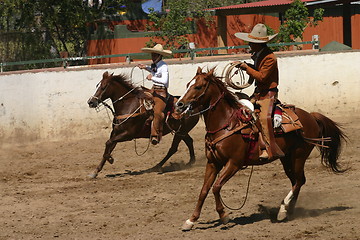 Image showing Two charros galloping