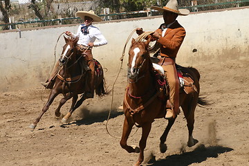 Image showing Two charros galloping