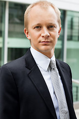 Image showing smiling successful business man in black suit outdoor