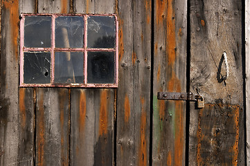 Image showing Old weathered and worn wooden planks with door and pink framed window