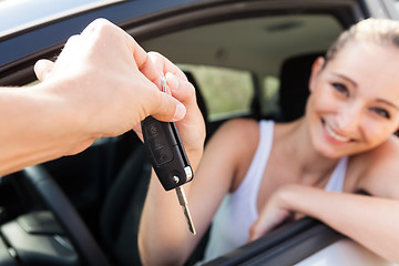 Image showing young smiling woman sitting in car taking key 