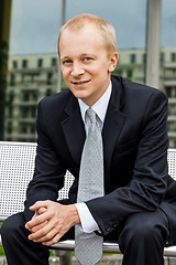 Image showing smiling successful business man in black suit outdoor