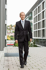 Image showing smiling successful business man in black suit outdoor