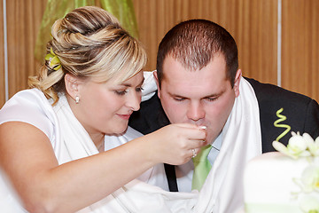 Image showing bride feeding her groom with spoon on wedding lunch