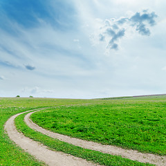 Image showing dirty road in green grass under cloudy sky