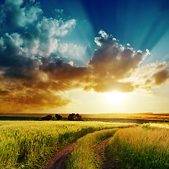 Image showing dramatic sunset over rural road in green field