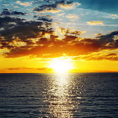 Image showing orange sunset over darken water