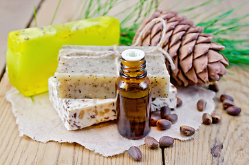 Image showing Oil and soap different with cedar nuts and cone on a board