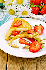 Image showing Pancakes with strawberries and cream on the board