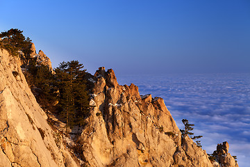 Image showing Sunlit rocks and sea in clouds at evening