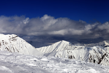 Image showing Ski slope and beautiful snowy mountains in clouds.
