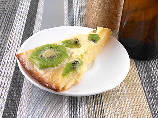 Image showing kiwi tasty cake close up at plate with vintage wine bottle