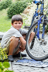 Image showing Teenager repairing his bike, changing broken tyre