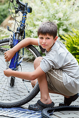 Image showing Teenager repairing his bike, changing broken tyre