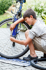 Image showing Teenager repairing his bike, changing broken tyre