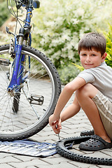 Image showing Teenager repairing his bike, changing broken tyre