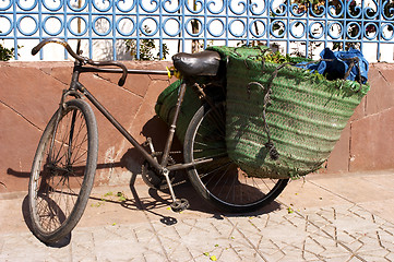 Image showing Old bicycle leaning against wall with panniers on the back