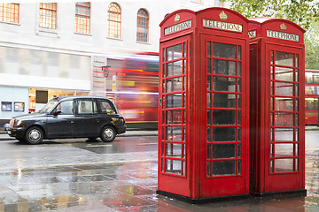 Image showing Red Phone cabines in London and vintage taxi.Rainy day.