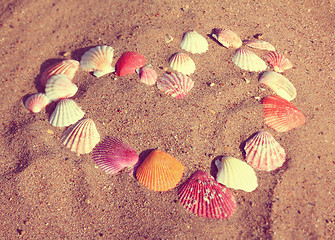 Image showing heart symbol from shells on sand - vintage retro style