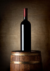 Image showing Bottle of wine on a barrel