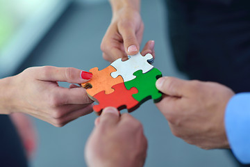 Image showing Group of business people assembling jigsaw puzzle