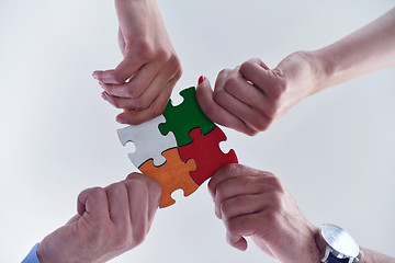 Image showing Group of business people assembling jigsaw puzzle