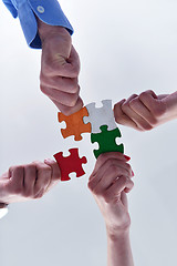 Image showing Group of business people assembling jigsaw puzzle