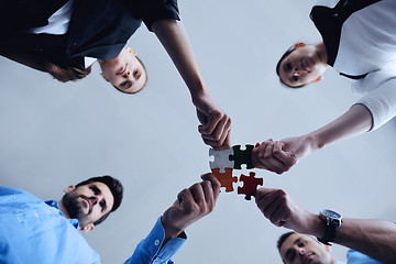 Image showing Group of business people assembling jigsaw puzzle