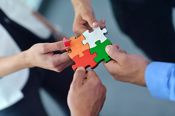 Image showing Group of business people assembling jigsaw puzzle