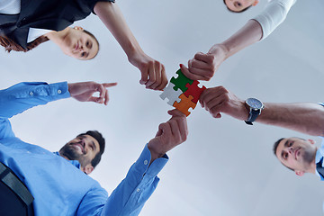 Image showing Group of business people assembling jigsaw puzzle