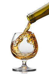 Image showing Cognac pouring into glass with splash isolated on white backgrou