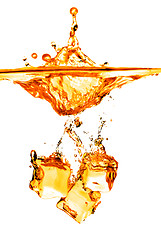 Image showing ice cubes dropped into orange water with splash isolated on whit