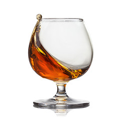 Image showing Splash of cognac in glass isolated on white background