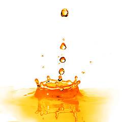 Image showing drop falling into orange water with splash isolated on white