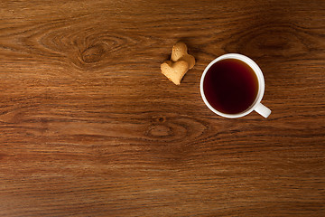 Image showing hot cup of tea with cookies on wooden table