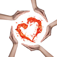 Image showing Red heart from water splash with human hands isolated on white
