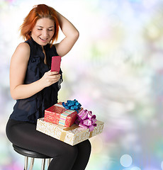 Image showing Emotional smiling woman with boxes gifts and phone on a festive 