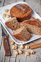 Image showing sliced fresh buns, old knife,hazelnuts and cinnamon sticks 