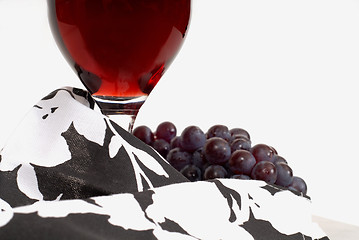 Image showing Low view of a wine glass with wine and grapes and napkin