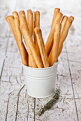 Image showing white bucket with bread sticks grissini and rosemary 