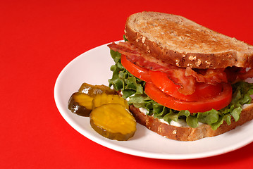 Image showing Bacon, lettuce and tomato sandwich with pickles, red background